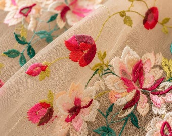 Puede incluir: Una tela de malla beige transparente con intrincados bordados florales. El diseño muestra flores vibrantes en tonos rojos, rosas y blancos, complementadas con tallos y hojas verdes, creando un patrón botánico detallado en el tejido.