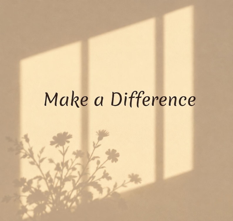May include: A beige wall featuring the dark brown text Make a Difference centered in the frame. The surface displays a soft shadow cast by a window frame and a floral arrangement, creating a light and dark contrast across the flat plane.