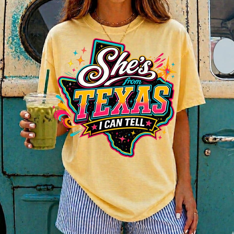 Pu&ograve; includere: Una t-shirt a maniche corte giallo pallido con una grafica dello stato del Texas in nero con un bordo colorato. Il testo recita She's from TEXAS I CAN TELL in lettere bianche, rosa e gialle, accentuato da piccole forme a stella e ghirigori.