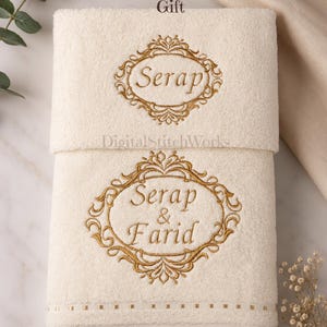 Peut inclure: Deux serviettes pliées de couleur crème avec des broderies dorées. La serviette supérieure porte le nom "Serap" dans un cadre ovale. La serviette inférieure porte la broderie "Serap & Farid". Le texte en haut indique "Cadeau de mariage personnalisé".