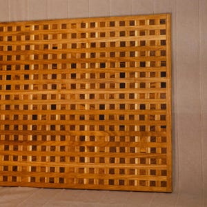 Può includere: Un tagliere rettangolare in legno caratterizzato da un complesso motivo a griglia. La superficie è composta da piccoli pezzi quadrati di legno intrecciati in varie tonalità di marrone chiaro, medio e scuro, creando un aspetto a scacchiera.