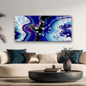 May include: A rectangular wall clock featuring a vibrant blue and purple agate stone pattern. The clock face displays white Roman numerals and thin white clock hands centered over the abstract, crystalline mineral design.