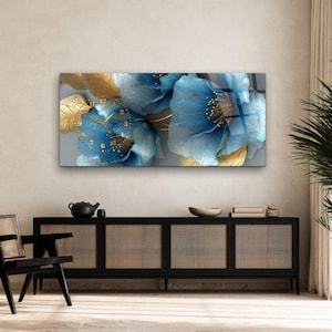 May include: A rectangular wall clock featuring a large-scale print of blue flowers with gold-toned accents and delicate gold stamens. The clock face is integrated into the floral design, displaying gold numerals and thin gold hands.