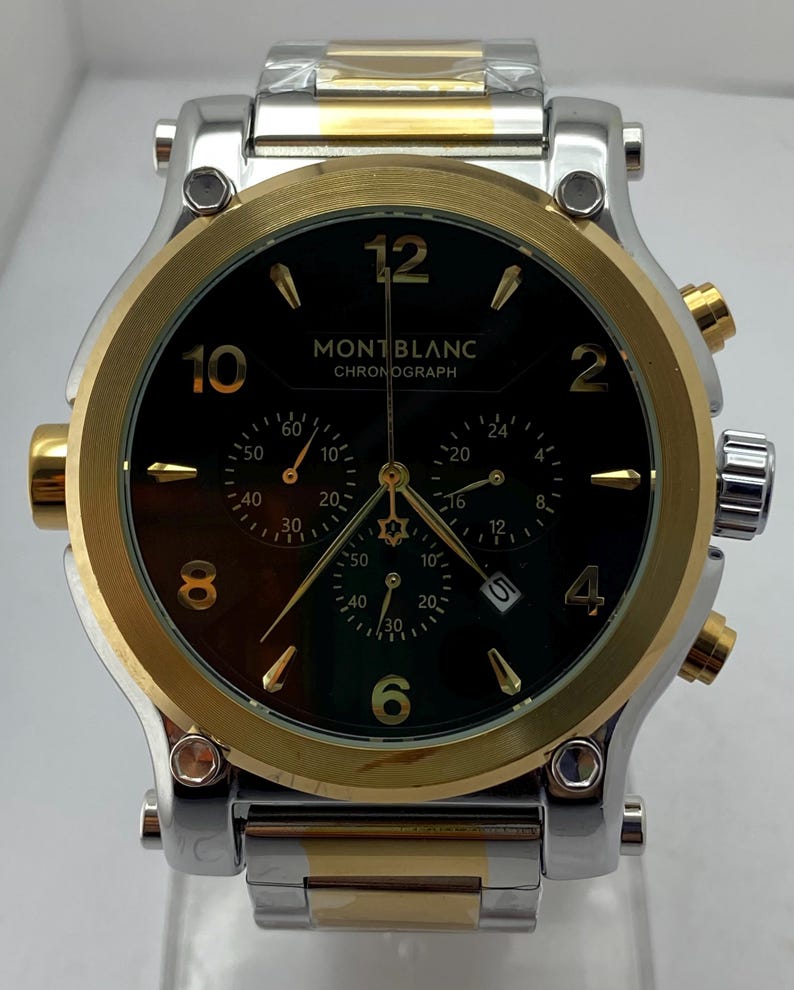 Może przedstawiać: Zegarek chronograf Montblanc z czarną tarczą, złotymi cyframi i złotymi wskaz&oacute;wkami. Zegarek posiada dwukolorową bransoletę ze stali nierdzewnej w kolorze srebrnym i złotym, złotą lunetę oraz trzy tarcze pomocnicze z datownikiem na godzinie czwartej.
