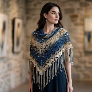 Pode incluir: Um xale triangular de crochê com um padrão degradê de fios azul-marinho profundo e dourado metálico. O acessório é detalhado com um design intrincado de pontos abertos, pequenas contas embutidas e longas franjas fluidas na borda inferior.