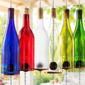 May include: A row of seven hanging glass bottles in blue, red, frosted white, clear, yellow, green, and brown. Each bottle is suspended by a silver metal chain that runs through the center, featuring a cork stopper and a copper-toned metal base.