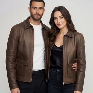 Puede incluir: Dos chaquetas de cuero marrón a juego con cuello clásico, cremallera frontal completa y dos bolsillos delanteros con solapa. Las chaquetas presentan mangas largas con puños y una textura suave y uniforme en todo el material de cuero.
