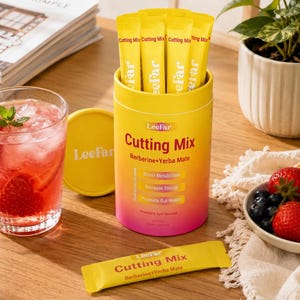 Puede incluir: Un recipiente cil&iacute;ndrico amarillo y rosa con sobres de "Cutting Mix", de la marca "LeeFar". Junto a &eacute;l, un vaso de bebida roja con hielo y menta, un cuenco peque&ntilde;o de bayas y un sobre de "Cutting Mix".