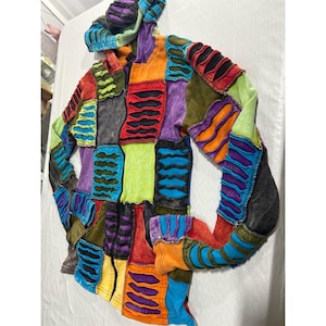 May include: A long-sleeve zip-up hoodie featuring a patchwork design of multi-colored fabric panels. Each panel displays a series of horizontal, distressed cut-out slits revealing a dark fabric layer underneath. The garment includes a hood.