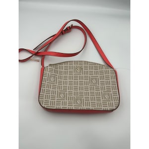 May include: A rectangular crossbody bag with a red strap and trim. The bag features a beige and brown geometric pattern with lion head emblems. A gold-colored emblem is centered on the front.
