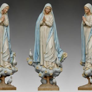 Puede incluir: Estatua religiosa de una mujer con una túnica blanca y azul claro, con las manos juntas en oración. La estatua está sobre una base de nube con palomas y flores.