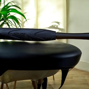 May include: A black massage chair with a curved seat and armrest. The armrest has the word "SPLICE" printed on it. The chair has a dark brown arm and legs.