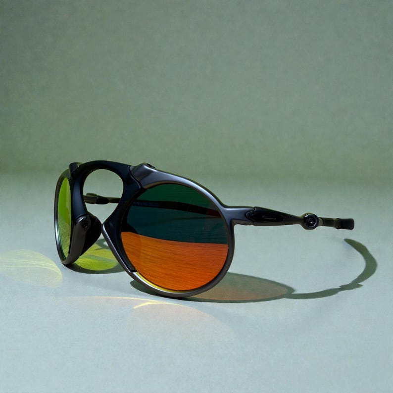 May include: Black sunglasses with a unique design. The lenses have a gradient of colors, transitioning from green to orange. The frames are black and have a distinctive shape, with a curved arm and a circular lens.