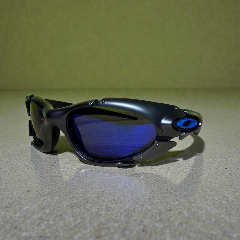 May include: Black sunglasses with blue lenses. The sunglasses have a sleek, modern design with a curved frame and a small blue accent on the side. The lenses are a vibrant blue color.