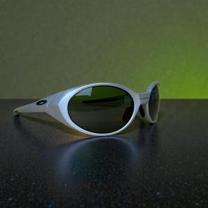 Op de afbeelding: Zilverkleurige zonnebril met donkere glazen. De zonnebril heeft een strak, modern design met een gebogen montuur en ovale glazen. De glazen zijn donker en bieden schaduw. Ze liggen op een donker oppervlak en een groene gradi&euml;nt achtergrond.