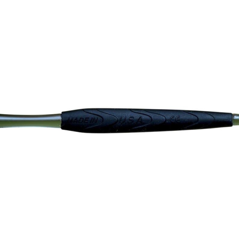 May include: Close-up of a black handle with the text "MADE IN USA" printed in white. The handle has a textured, ridged design for grip and a green section near the end.