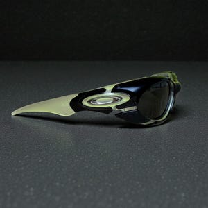 以下が含まれることがあります： 黒と白のフレームと濃い色のレンズを備えたスポーティーなサングラス。 サングラスは、湾曲した形状と側面の目立つロゴを備えた、洗練された空気力学的なデザインです。
