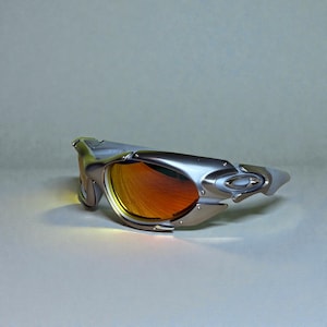 May include: Silver-framed sunglasses with orange lenses. The sunglasses have a futuristic design with a curved frame and a sleek, modern aesthetic. The lenses reflect a warm, orange hue.