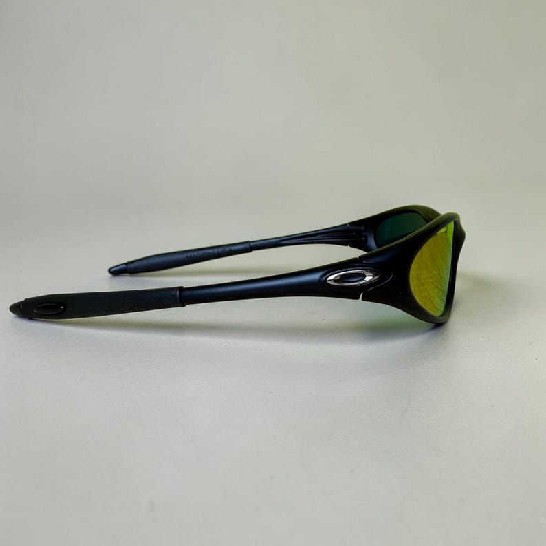 May include: Black sunglasses with a curved frame and yellow-green lenses. The sunglasses have a sleek, modern design with a silver accent on the frame. The arms are thin and extend back to the ear pieces.