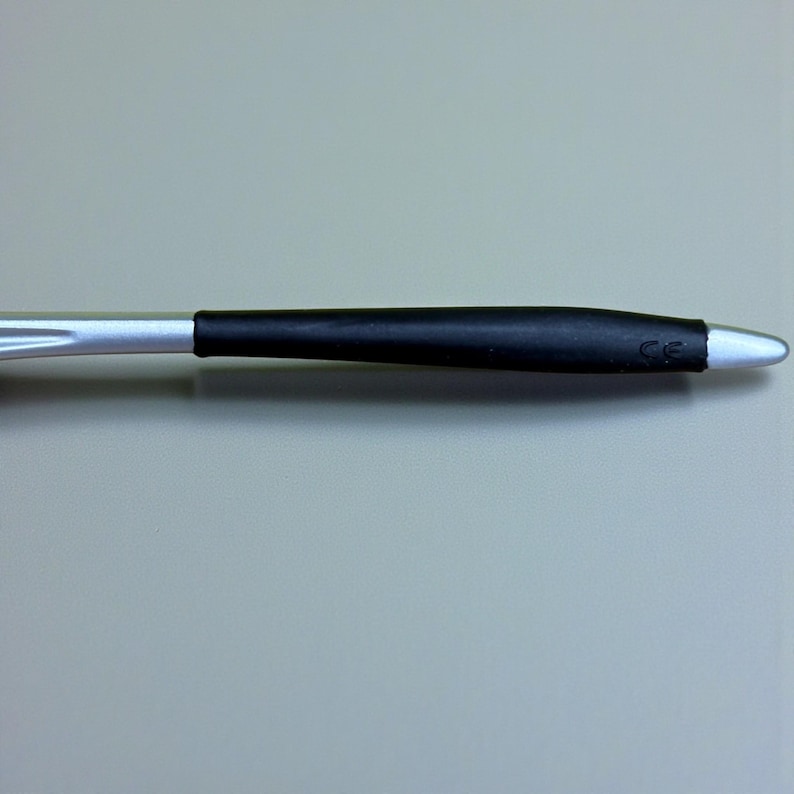 Op de afbeelding: Een zilveren en zwarte pen met een zwarte rubberen grip. De pen heeft een zilveren punt en de letters "CE" zijn gedrukt op de zwarte grip. De pen staat tegen een grijze achtergrond.