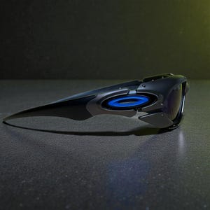 May include: Black and gray sunglasses with a futuristic design. The sunglasses feature a blue circular accent and dark lenses. The sleek, aerodynamic shape suggests a sporty or high-performance aesthetic.