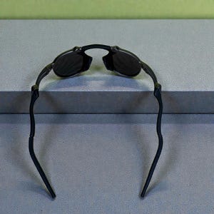 May include: Black sunglasses with a curved frame and dark lenses. The sunglasses have a sleek, modern design, suitable for outdoor activities. The arms of the sunglasses are thin and extend outward.