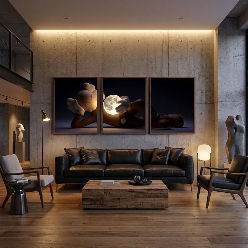 May include: A triptych wall art set featuring a stylized cartoon character with X-shaped eyes lying down and holding a glowing, luminous moon. The three framed prints are displayed horizontally above a black leather sofa in a living room.