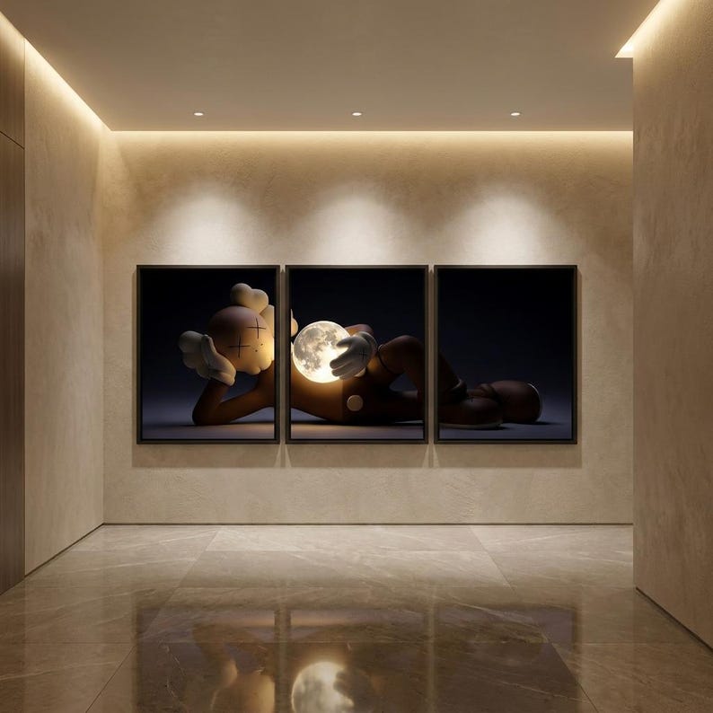May include: A triptych wall art set featuring a brown cartoon character with X-shaped eyes lying down and holding a glowing, spherical moon. The artwork is displayed in three black frames against a neutral wall, creating a cohesive visual scene.