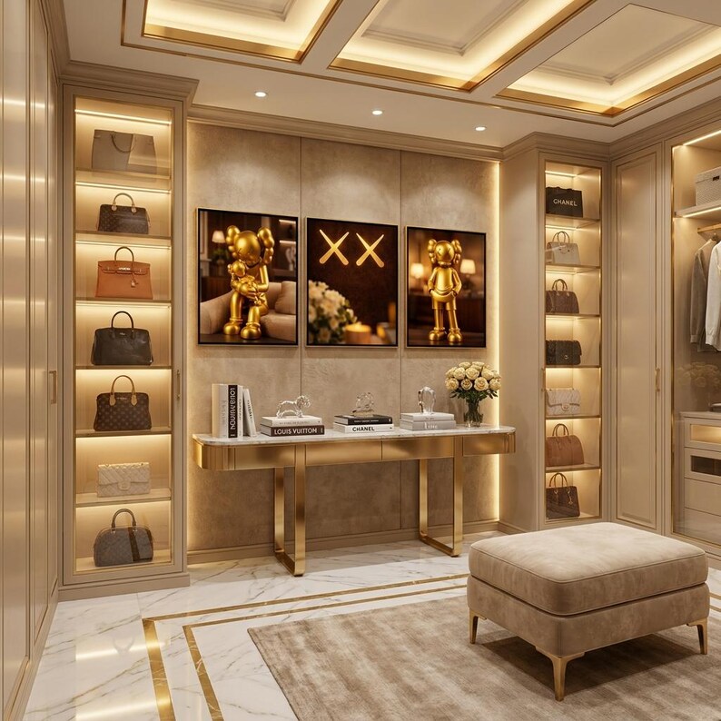Pu&ograve; includere: Una cabina armadio con scaffali in vetro illuminati pieni di varie borse, un tavolo console centrale con piano in marmo e cornice dorata, tre opere d'arte incorniciate a parete e un pouf beige imbottito su un pavimento in marmo.
