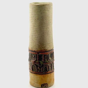 May include: A tall, cylindrical ceramic vase with a textured, light beige upper section and a darker, earthy base. The middle band features a repeating embossed pattern in shades of reddish-brown and dark green, with a small stamped mark near the bottom.