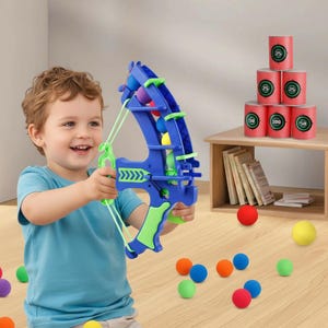 Könnte beinhalten: Ein blauer und lindgrüner Spielzeugbogen mit Schnurmechanismus zum Abschießen kleiner Schaumstoffbälle. Das Set enthält einen Stapel aus sechs roten, mit Punktwerten markierten Zylinderzielen sowie mehrere bunte Schaumstoffbälle am Boden.