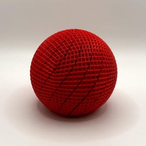 May include: A vibrant red sphere with a unique, grid-like texture. The spherical object is made of interwoven red material, creating a visually striking geometric pattern. The design suggests a modern, artistic aesthetic.