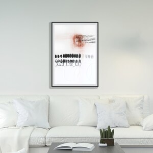 Puede incluir: Impresión de arte abstracto en un marco negro. La obra presenta un fondo blanco con pinceladas, puntos y líneas negras y rojas. El arte enmarcado cuelga sobre un sofá blanco con cojines blancos.