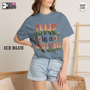 Ice Blue Comfort Colors 1717 t-shirt with watercolor watermelon graphic, styled with denim shorts on female model
