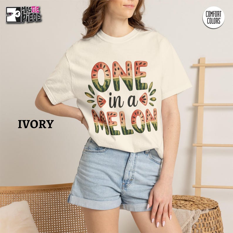 Ivory Comfort Colors 1717 t-shirt with One in a Melon watermelon graphic, styled with denim shorts on female model