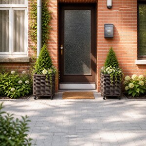Peut inclure: Façade en briques rouges avec une porte marron foncé et un panneau de verre texturé. Deux jardinières en osier marron foncé avec de petits conifères et des fleurs blanches encadrent l'entrée. Un paillasson est devant la porte.