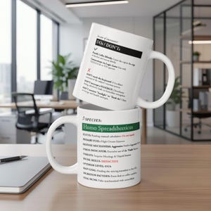 Op de afbeelding: Twee witte keramische mokken gestapeld op een houten bureau. De bovenste mok heeft tekst over "DOs/DON'Ts" en de onderste mok "SPECIES: Homo Spreadsheeticus" met extra tekst. De mokken staan in een kantooromgeving.