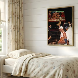 May include: A framed wall art print featuring a photograph of a basketball player holding a trophy with the text Chicago Bulls 1992 NBA World Champion visible on a scoreboard in the background, displayed in a room with floral bedding.