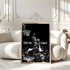 May include: A framed black and white print depicting a basketball player in action, about to score. The print has the text "Tell Me I Can't" in white. The artwork is displayed in a living room setting.