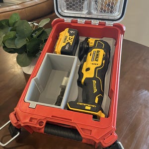 May include: A red plastic tool storage case with a clear lid containing a yellow and black DeWalt 20V XR battery, a yellow and black DeWalt oscillating multi-tool, and a grey plastic insert tray holding a metal cutting blade attachment.