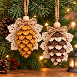May include: Two crocheted pinecone ornaments with cream-colored lace backings. Each features a central wooden bead, a brown twine bow, and a matching twine hanging loop. One pinecone is golden yellow, and the other is dark brown and cream.