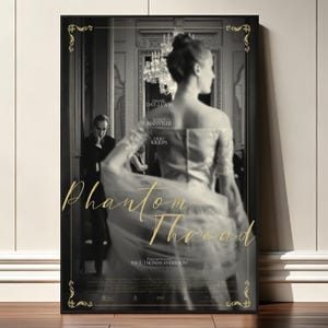 May include: A black and white movie poster for Phantom Thread featuring a person in a gown facing away from the camera, with a man in a suit standing in the background. The title Phantom Thread is written in gold script, with gold ornate corner borders.