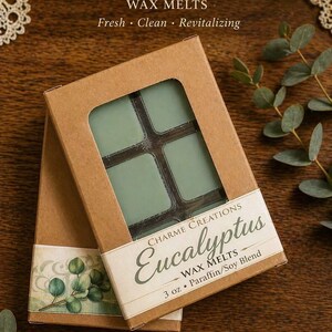 May include: Two boxes of eucalyptus wax melts. The boxes are brown with a window showing four green wax melt squares. The boxes have the words "Eucalyptus Wax Melts" and "3 oz. Paraffin/Soy Blend" printed on them. The text "Fresh, Clean, Revitalizing" is also visible.