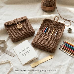 Puede incluir: Un kit de artesano de ganchillo marrón con una bolsa, lápices y una regla. El kit incluye una bolsa artesanal con un botón de madera y la letra "A". El kit también incluye una tarjeta que dice "The Artisan's Kit".
