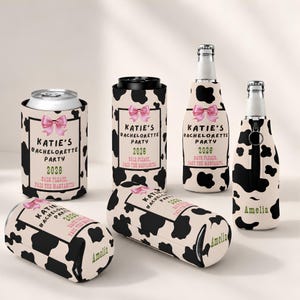 May include: A collection of beverage insulators featuring a black and white cow print pattern. Each item displays a pink bow, the text "Katie's Bachelorette Party 2026", and "Bach Please, Pass The Margarita". Some items are personalized with the name "Amelia".