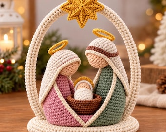 May include: A crochet nativity scene featuring two figures in pink and green robes with yellow halos, standing under a cream-colored arch topped with a yellow star. A small figure in white is nestled in a brown cradle between them.