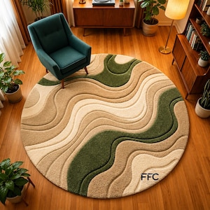 May include: A round area rug with a wavy pattern in shades of beige, tan, and green. The rug has a soft, textured appearance and is placed on a hardwood floor. The rug's design creates a sense of depth and movement.