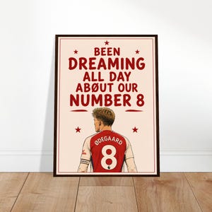 May include: Framed print featuring a stylized illustration of a soccer player wearing a red jersey with the number 8. The print includes the text "Been Dreaming All Day About Our Number 8" in red, with star accents.