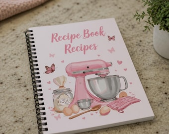 May include: A spiral-bound recipe book with a white cover featuring the text Recipe Book Recipes in pink. The cover displays a pink stand mixer, a glass jar labeled Flour, a wooden spoon, three eggs, and a pink oven mitt, all surrounded by small pink butterflies and hearts.