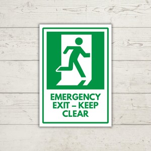 May include: A rectangular emergency exit sign featuring a green background with a white border and a white graphic of a person running through an open doorway. Below the graphic, the text reads EMERGENCY EXIT – KEEP CLEAR in white.
